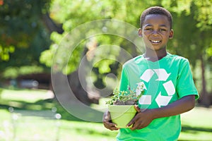 Young boy in recycling tshirt holding potted plant