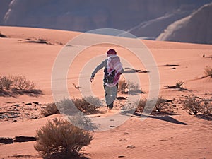 Young boy on the red sand dunes of the Wadi Rum desert, Jordan