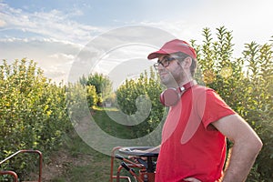 Young boy in a red t-shirt and cap drives an apple picker in a fruit field