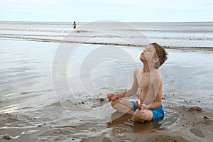 Mladý chlapec relaxační v jóga póza na pláž 