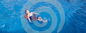 Young boy relaxing in the swimming pool.