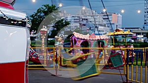 A young boy rides a children`s carousel in the evening. Children`s rest