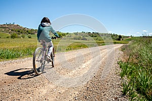 A young boy is riding a bike down a dirt road