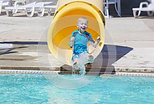 Young boy riding down a yellow water slide