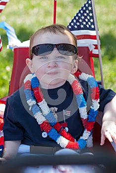 Young boy riding in red wagon having fun in the park for July Fourth