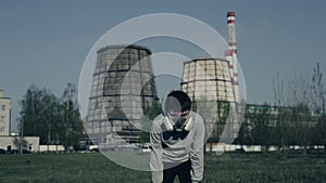 Young boy run against of factory chimneys. Air pollution concept. Close up portrait of young guy witn plant on
