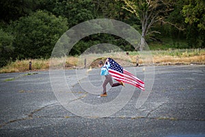 A young boy running while holding the American Flag showing patriotism for his own country, Unites States