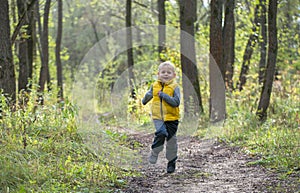 Young boy runs along a forest path