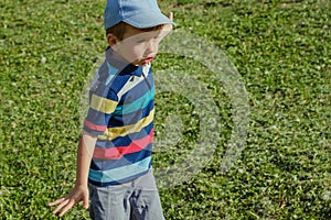 Young boy runs in a green field. Cute child running across park outdoors grass.