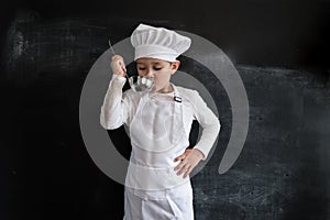 Young boy`s standing near blackboard checking soup. Young chef boy. Creative design concept for 2019 calendar.