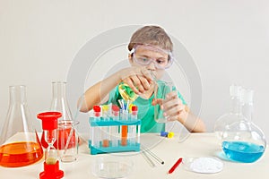 Young boy in safety goggles doing chemical experiments in laboratory