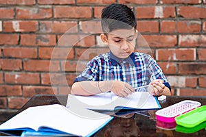 Young boy sharpening the pencil in classroom while attending class in primary School