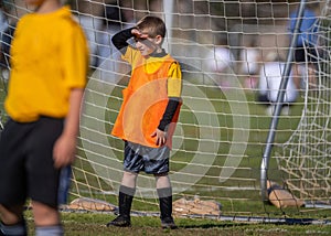 Young boy shielding his eyes as goalie during soccer match