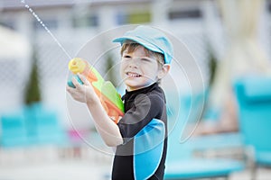 Young boy shooting water gun outdoors