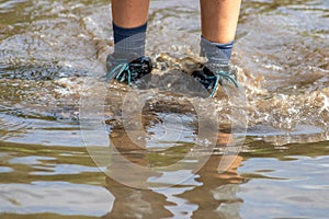 Young boy with short blue trowsers wading with wet socks and wet boots through high tide after a floodwater