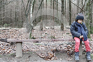 Young boy sitting alone on a rustic bench