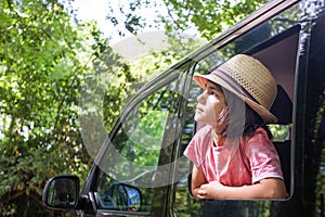 A young boy is sitting in a car with her hat on