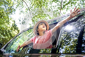 A young boy is sitting in a car window, looking out at the trees