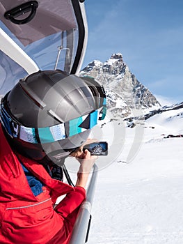 A young boy, sitting on a chairlift, takes a photo of the Matter