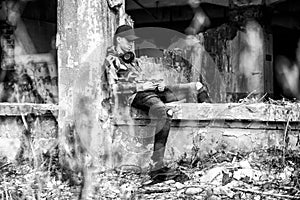 Young boy sitting on a crumbling building and using smarthphone