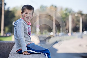 Young boy sitting on edge of the granite curb, copyspace