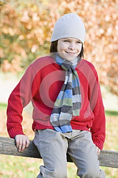 Young boy sitting on fence
