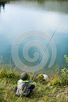 Young boy sitting and fishing