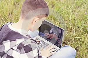 Cheerful teenager chatting on modern laptop