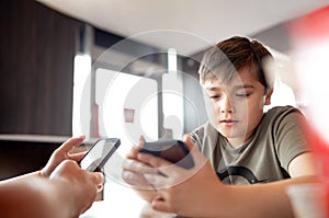 Young boy sitting with parent using mobile phone,Man hand holding smart phone ordering food in restaurant,Kid playing game or