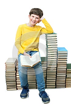 Young boy sitting on stacks of books and reading