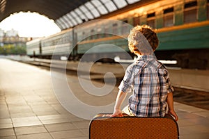 Young boy sitting on suitcase