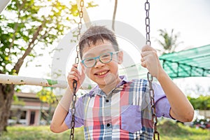 Young boy sitting on swing chair and smiles