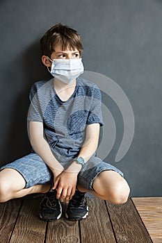 Young boy sitting and wearing a protective mask