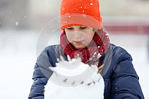 Young boy sledding from a hill, plays snowballs, makes snowman on winter holidays. Active lifestyle, winter activity