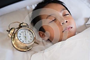 Young boy sleeping with alarm clock
