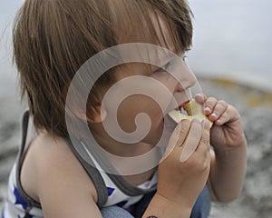 Young boy with a slice of apple