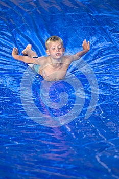 Young boy sliding down a slip and slide outdoors