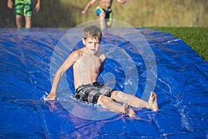 Young boy sliding down a slip and slide outdoors