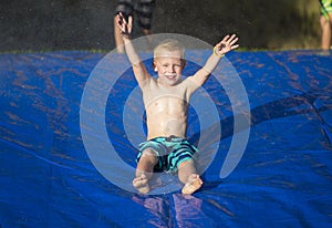 Young boy sliding down a slip and slide outdoors