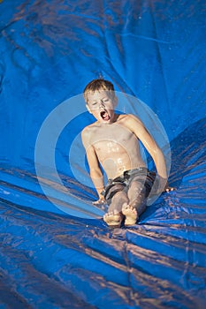 Young boy sliding down a slip and slide outdoors