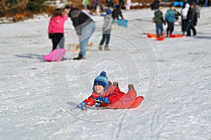 Young boy sliding snowy hill, winter fun