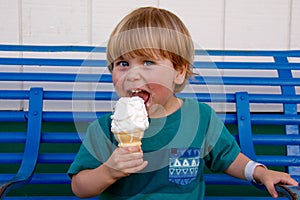 Young boy smiling while licking an ice cream cone