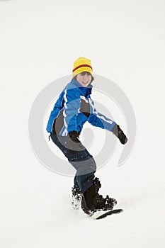 Young Boy Snowboarding Down Slope On Holiday