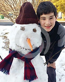 Young Boy with a Snowman That He Built