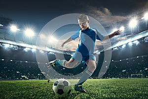 Young boy with soccer ball doing flying kick at stadium