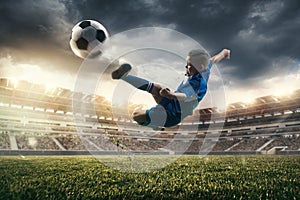 Young boy with soccer ball doing flying kick at stadium