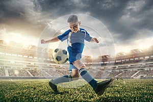 Young boy with soccer ball doing flying kick at stadium