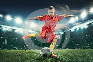 Young boy with soccer ball doing flying kick at stadium