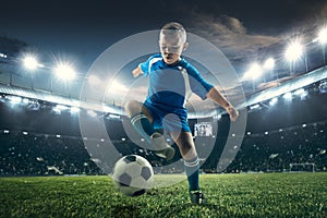 Young boy with soccer ball doing flying kick at stadium