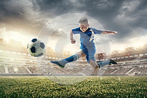 Young boy with soccer ball doing flying kick at stadium